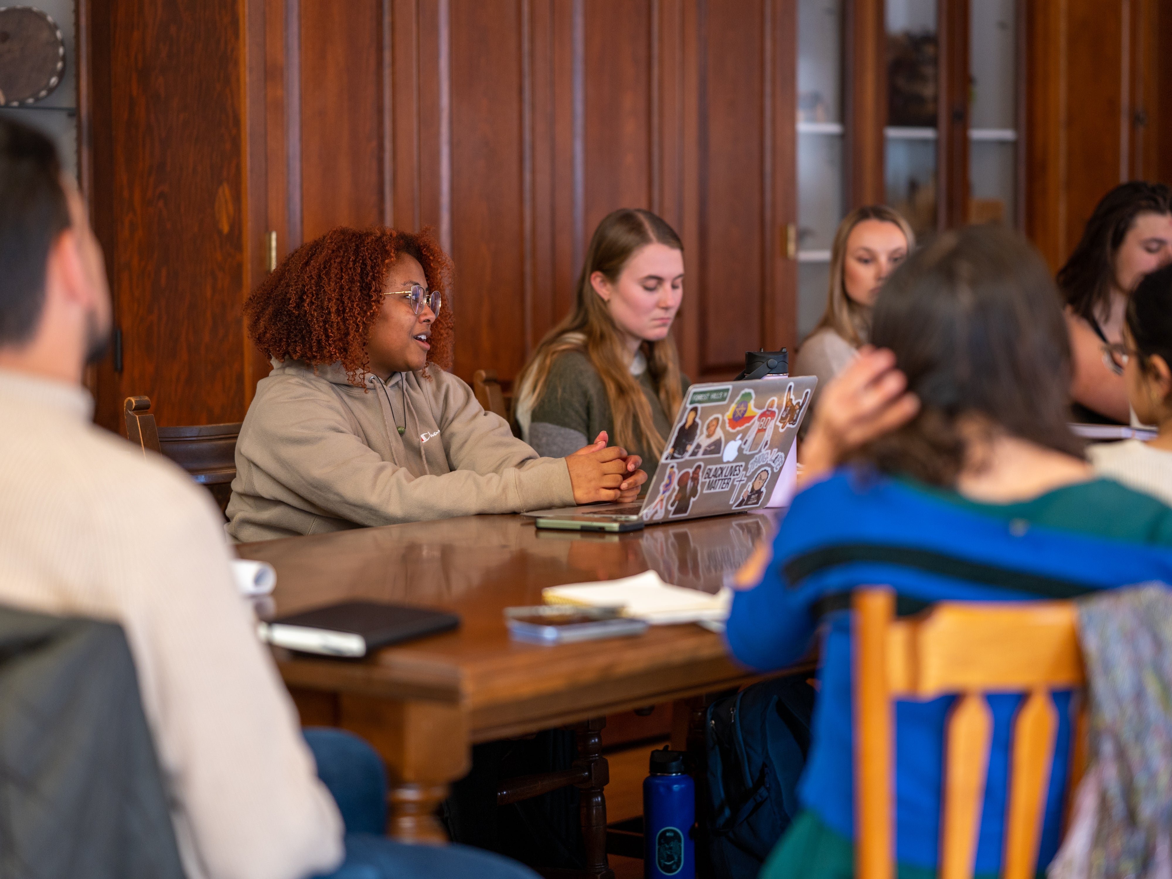 A student presenting information from a laptop to others at a table.