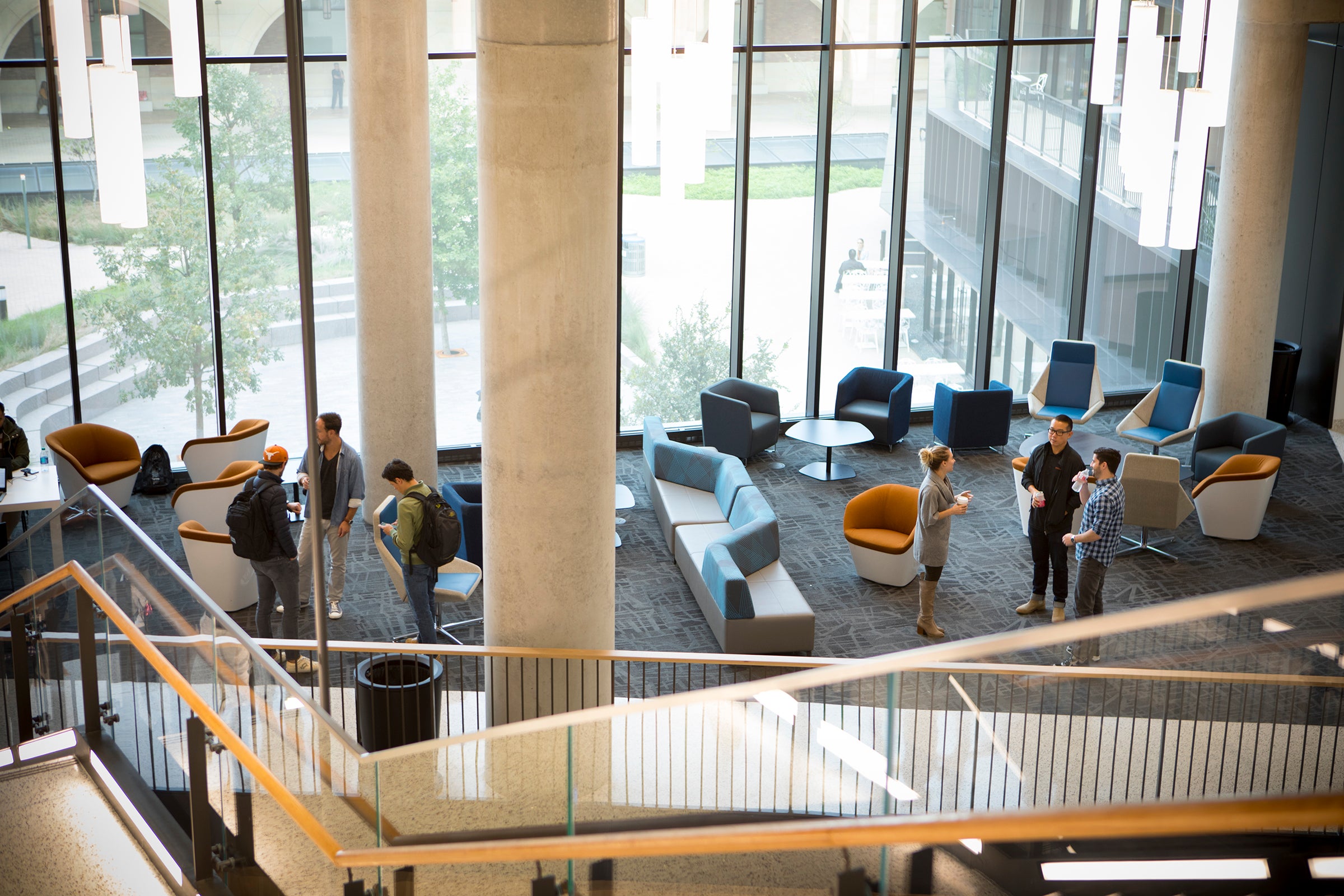 A lobby with various people talking, taken from the top of a staircase